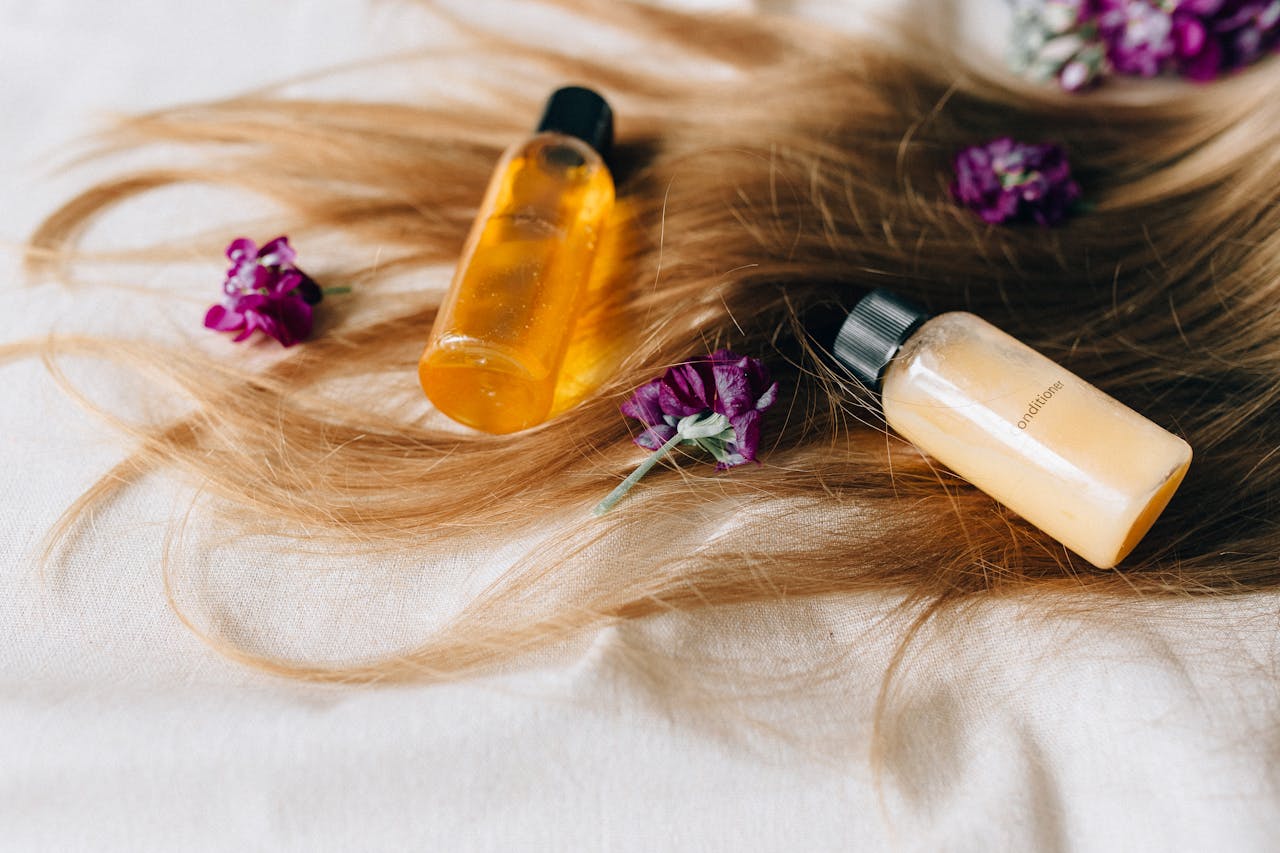 about-01 Hair care products on a bed of hair and flowers, symbolizing luxury and beauty.